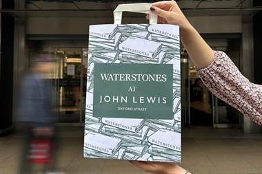 Close-up on a hand holding a paper bag printed with the words: Waterstones at John Lewis Oxford Street