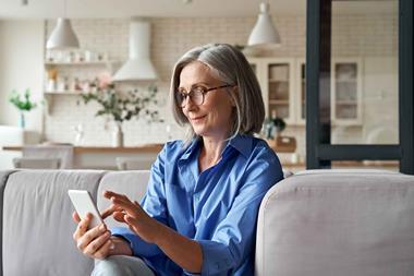 Over-50s woman shopping on phone on sofa