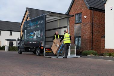 Two delivery drivers unloading a washing machine from a Marks Electrical van