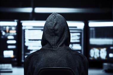 Hacker in a dark room with desktops