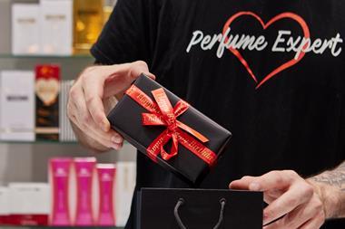 The Perfume Shop employee shown from the neck down putting a package in a gift bag