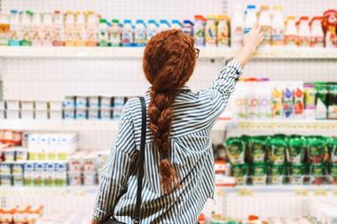 Woman lifting a product from a supermarket shelf