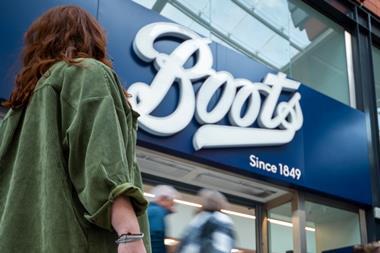 Woman walking past Boots sign carrying a shopping bag