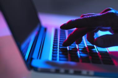 Hand typing on laptop keyboard at night