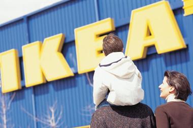 Exterior of Ikea store with a young family walking past, including a child on an adult's shoulders