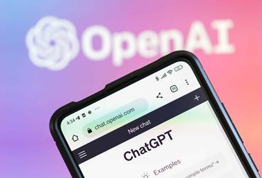 ChatGPT on phone with OpenAI logo in background