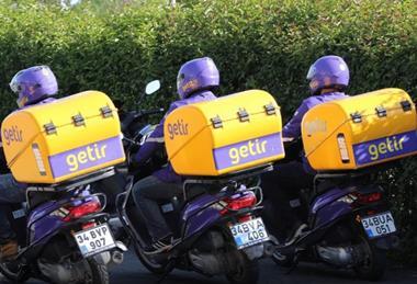 Three Getir delivery drivers on motorbikes shown from behind