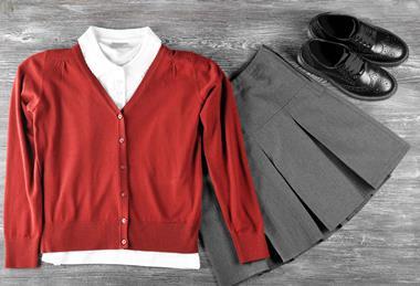 School uniform (red cardigan, white shirt, grey skirt and black shoes) on grey wooden background