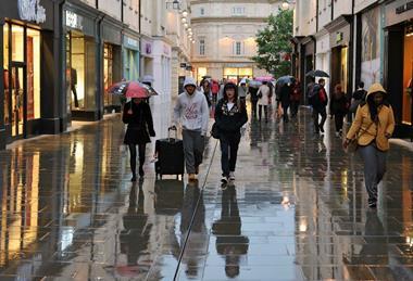 Shoppers walking in rain down Bath high street