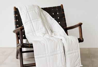Styled photo of a white Baloo blanket on a black chair