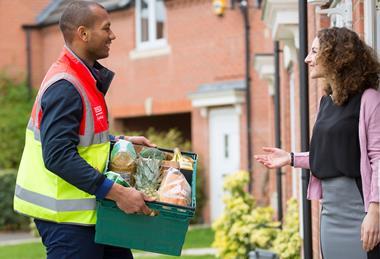 Tesco delivery worker handing groceries to customer at her door