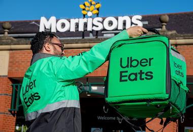 Uber Eats rider holding delivery bag outside Morrisons store