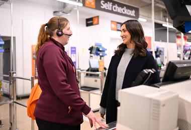 Sainsbury's employee wearing headset talking to customer in store