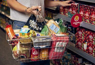 Customer carrying basket of groceries in Morrisons
