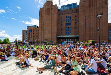 Crowd of people watching sporting event on big screen at Battersea Power Station