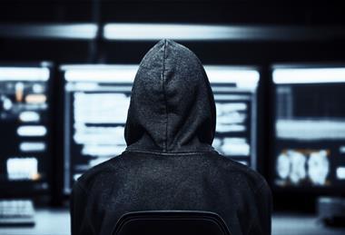 Hacker in a dark room with desktops
