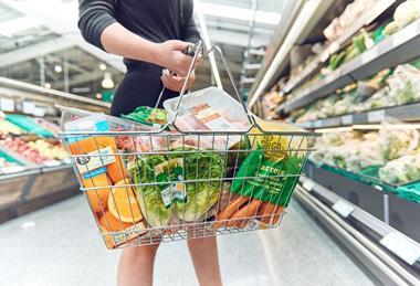 Woman holding shopping basket full of groceries