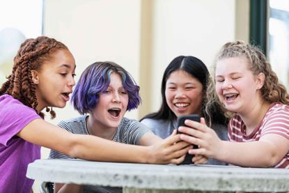 Four-girls-looking-at-a-phone-and-laughing