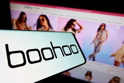 Boohoo logo on a phone in front of a website showing models