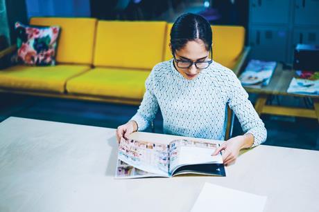 Woman looking through a catalogue sat at a desk