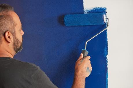 Man painting wall with blue paint