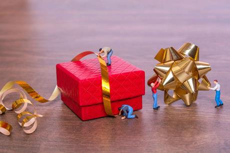 Toy-figures-wrapping-up-an-oversized-Christmas-present-with-ribbons index