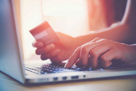 Close up on one hand typing on a laptop and the other holding a credit card