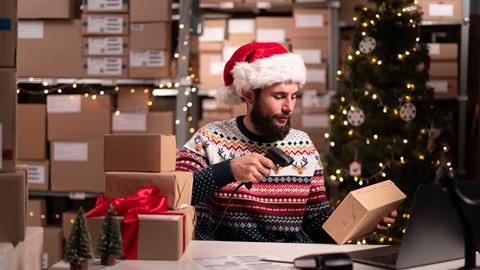 Man in Santa hat and Christmas jumper scanning parcel