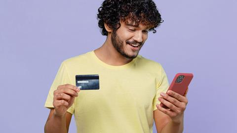 Image of a man smiling with a phone and a credit card