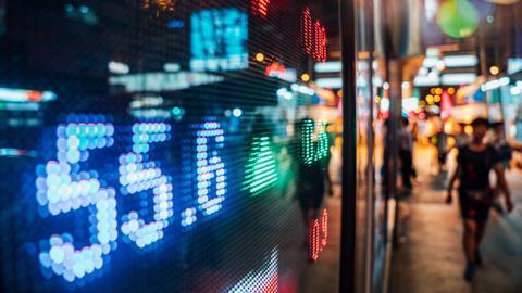 Stock market listings shown through the window of a busy street by night