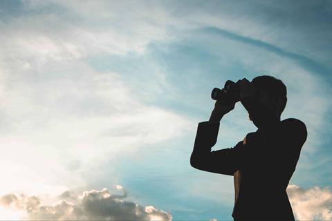 Silhouette of man looking through binoculars