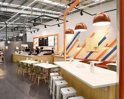 The cafe features pendant copper lights and 3D-style wall graphics and is located next to the order collection area.