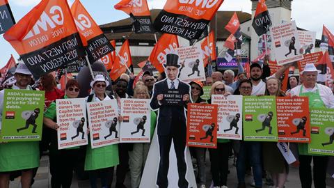 Asda workers on strike with flags and a cutout of TDR capital Manjit Dale