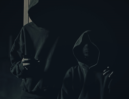 Two black figures, one taller and holding a phone, wearing black Yeezy Gap hoodies