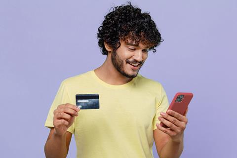 Image of a man smiling with a phone and a credit card