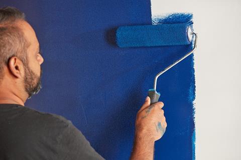 Man painting wall with blue paint