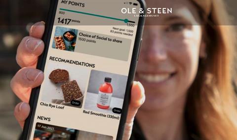 A woman holding a mobile phone featuring the Ole & Steen app, showing a series of special offers