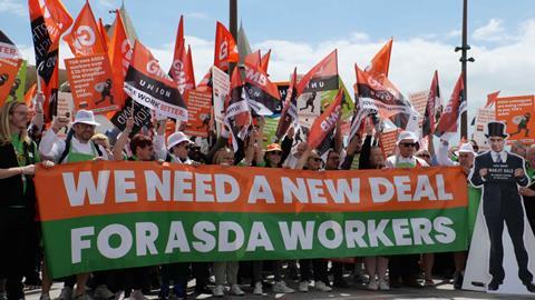 Striking workers at Asda holding placards, flags and a banner that reads: 'We need a new deal for Asda workers'