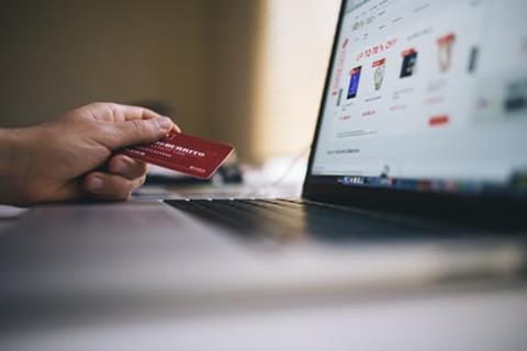 person holding credit card next to a laptop