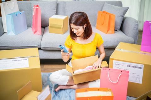 Woman sitting on her phone among her numerous packages from online shopping