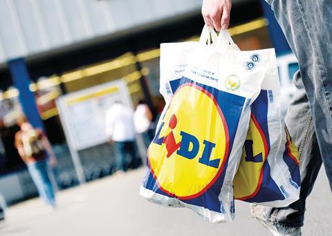 Close-up on a Lidl carrier bag being in the hands of a shopper walking down a high street