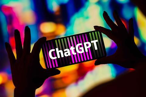 Two hands holding phone with ChatGPT logo on coloured background