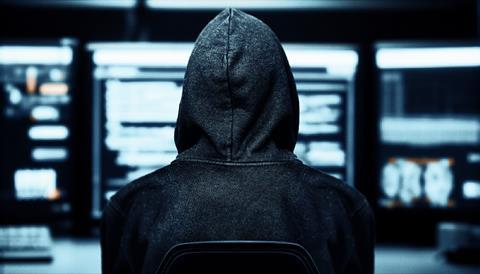 Hacker in a dark room with desktops