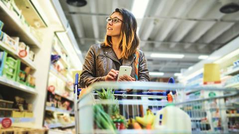Woman-shopping-in-supermarket-and-looking-at-phone
