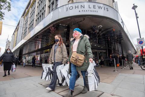 John Lewis Oxford Street with shoppers wearing Covid masks carrying shopping bags