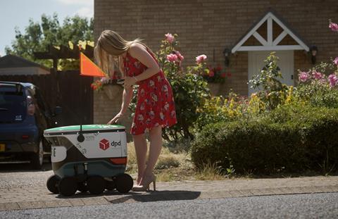 Woman receiving a delivery from a DPD robot outside a house